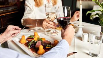 Una mesa de comedor con un plato de comida, copas de vino y una vela.