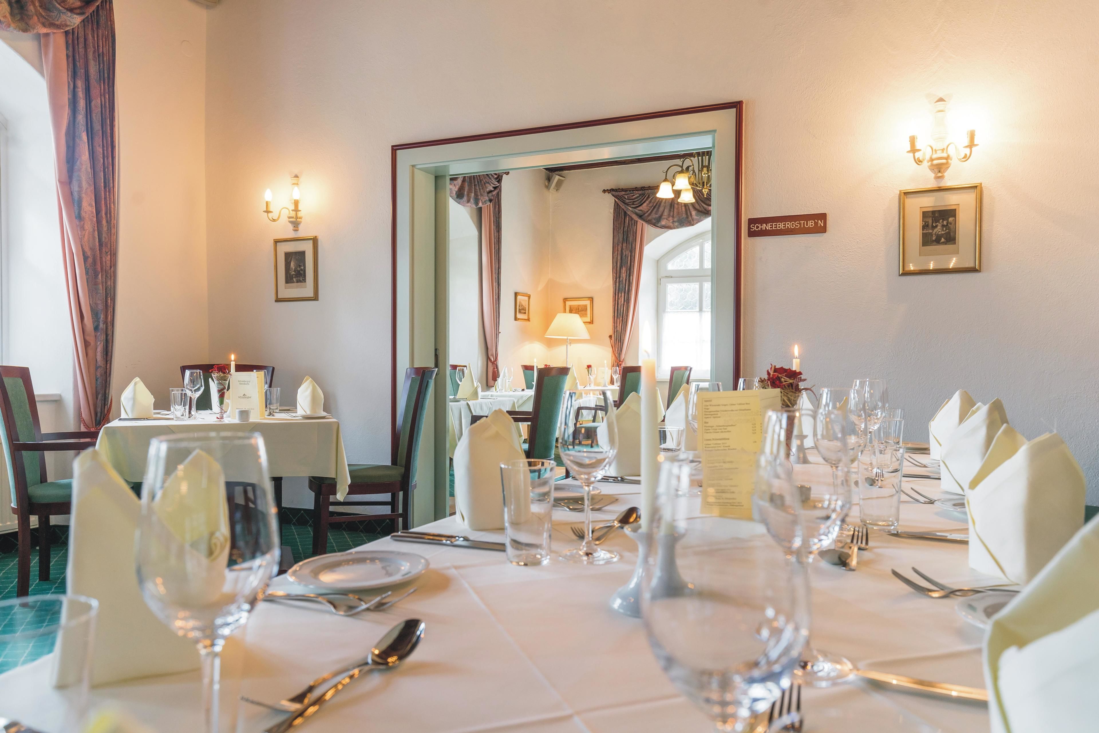 A dining area with tables set for a meal, including wine glasses, plates, and cutlery.