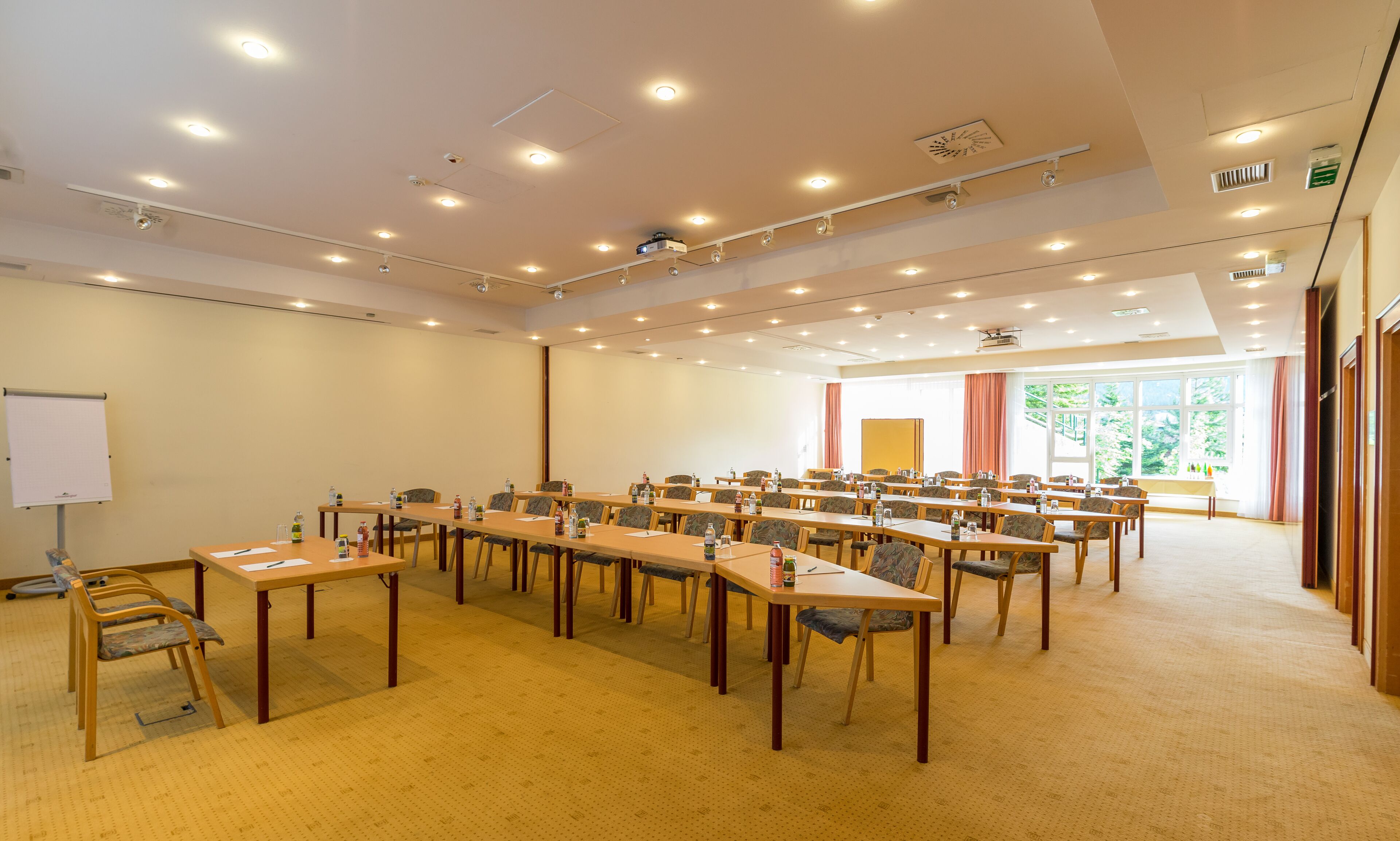 A conference room with multiple tables and chairs, a whiteboard, and a projector.