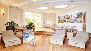 A modern spa area with wicker lounge chairs, a stone wall, and a ceiling with recessed lighting. - Schneeberghof (Puchberg Am Schneeberg)