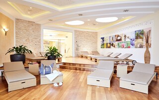Uma área de spa moderna com espreguiçadeiras de vime, uma parede de pedra e um teto com iluminação embutida.