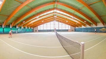 Ein Hallen-Tennisplatz mit hoher Decke und Holzbalken.