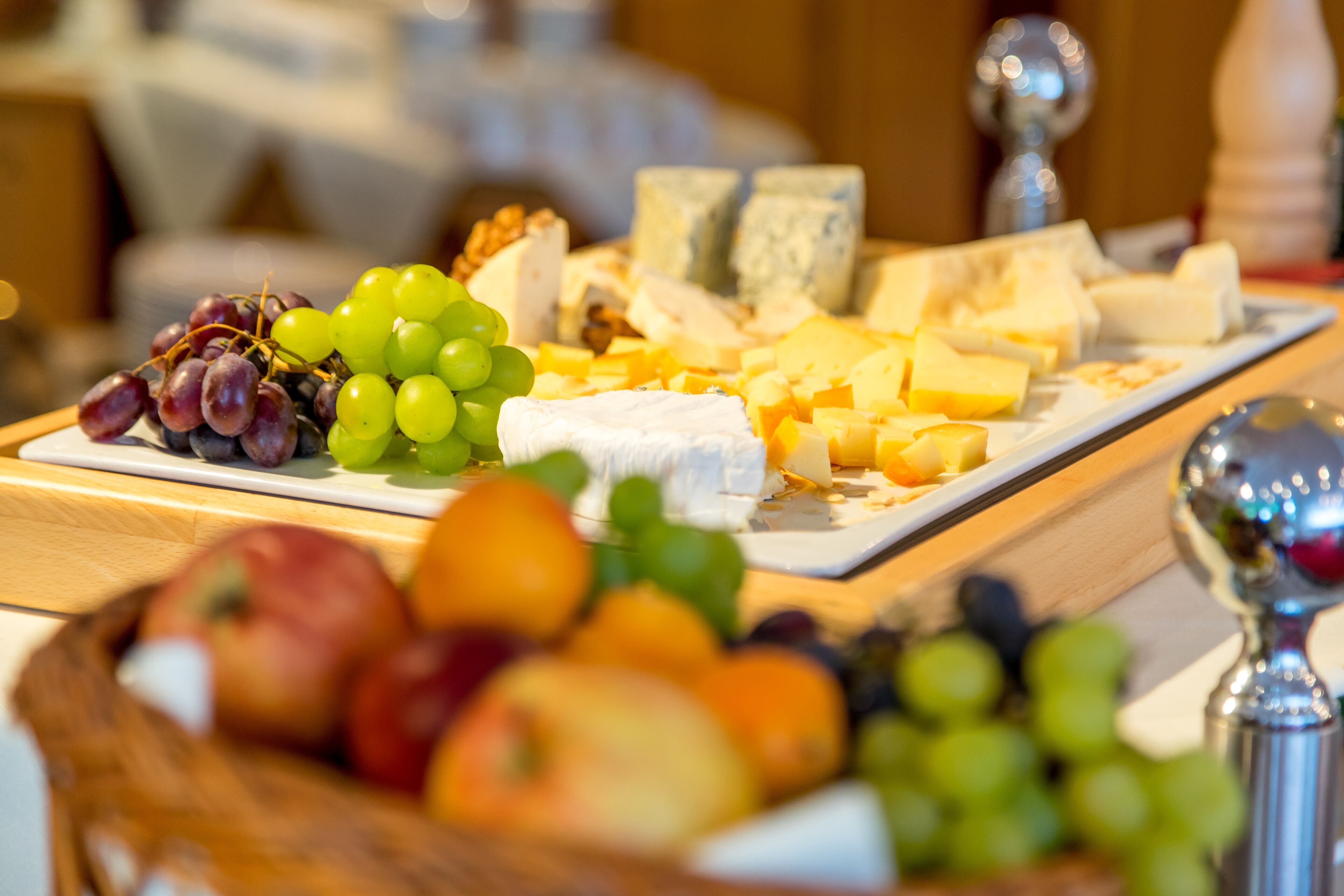 A cheese platter with various cheeses and fruits.