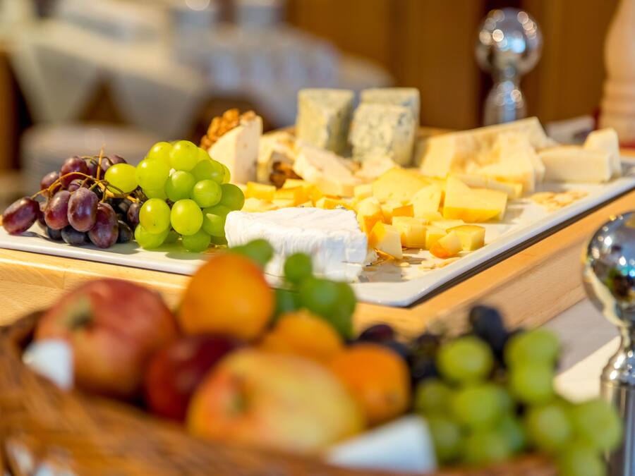 A cheese platter with various cheeses and fruits.