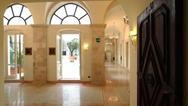 A spacious lobby with arched windows, a central door, and a chandelier. - Hotel San Paolo al Convento (Trani)