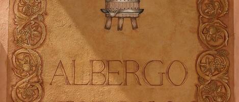 A framed artwork with a central wooden barrel and the name "Alberto Torcolo" embossed on it.