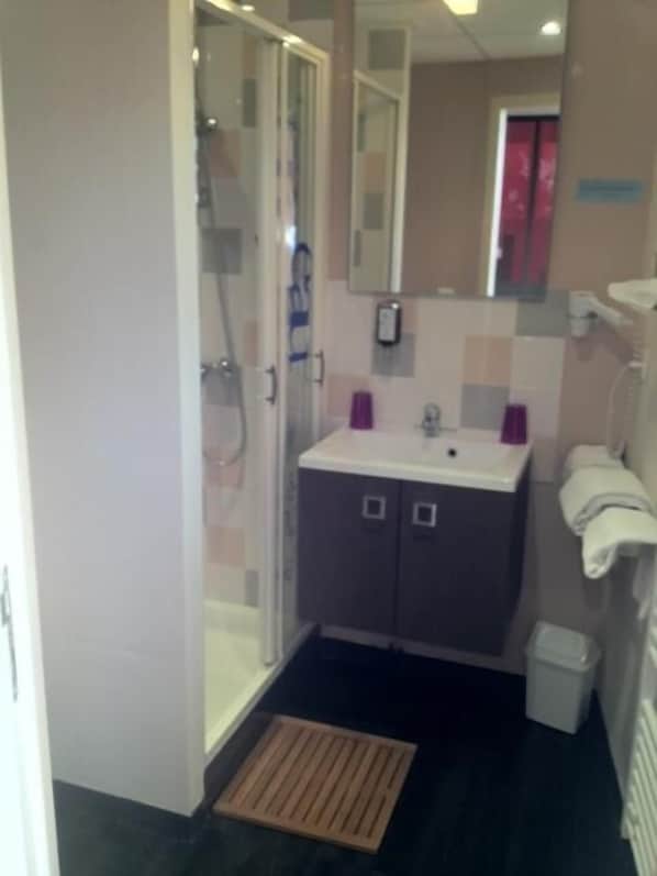 Un baño pequeño con ducha, lavamanos e inodoro.