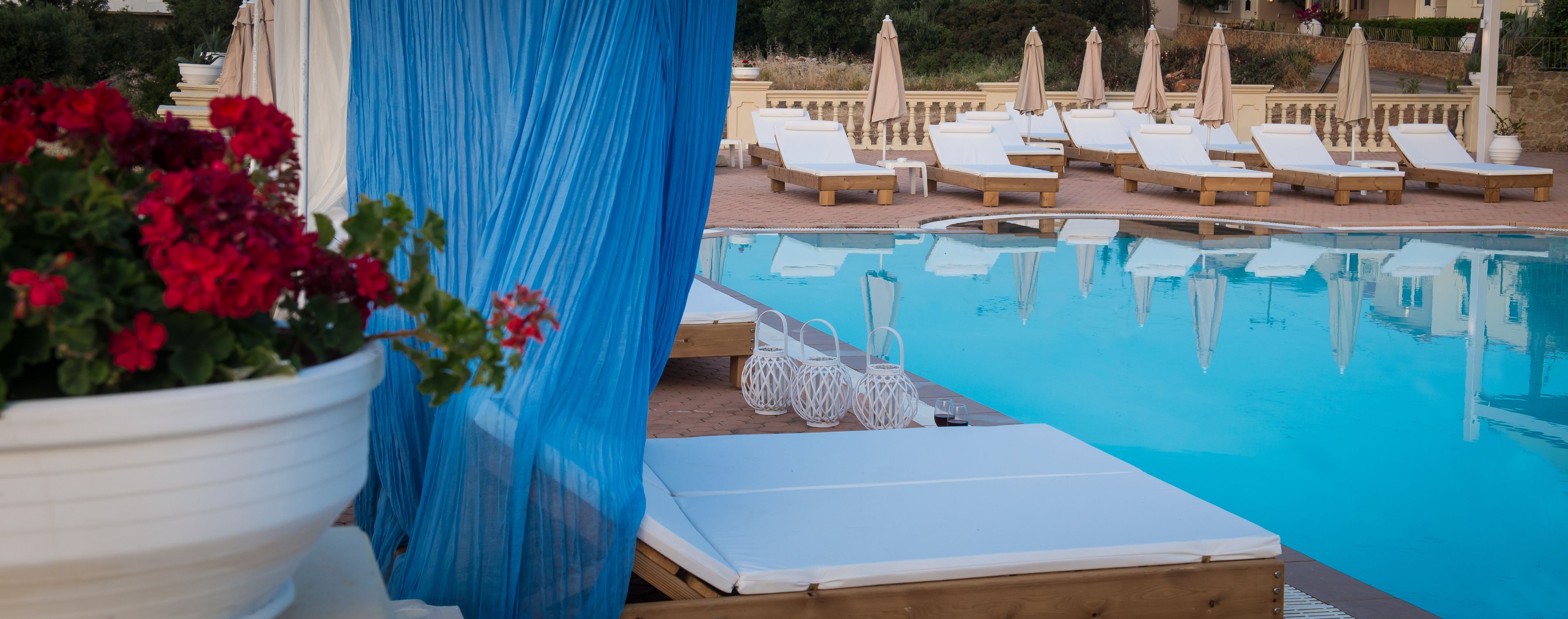 A pool area with lounge chairs and a blue curtain.