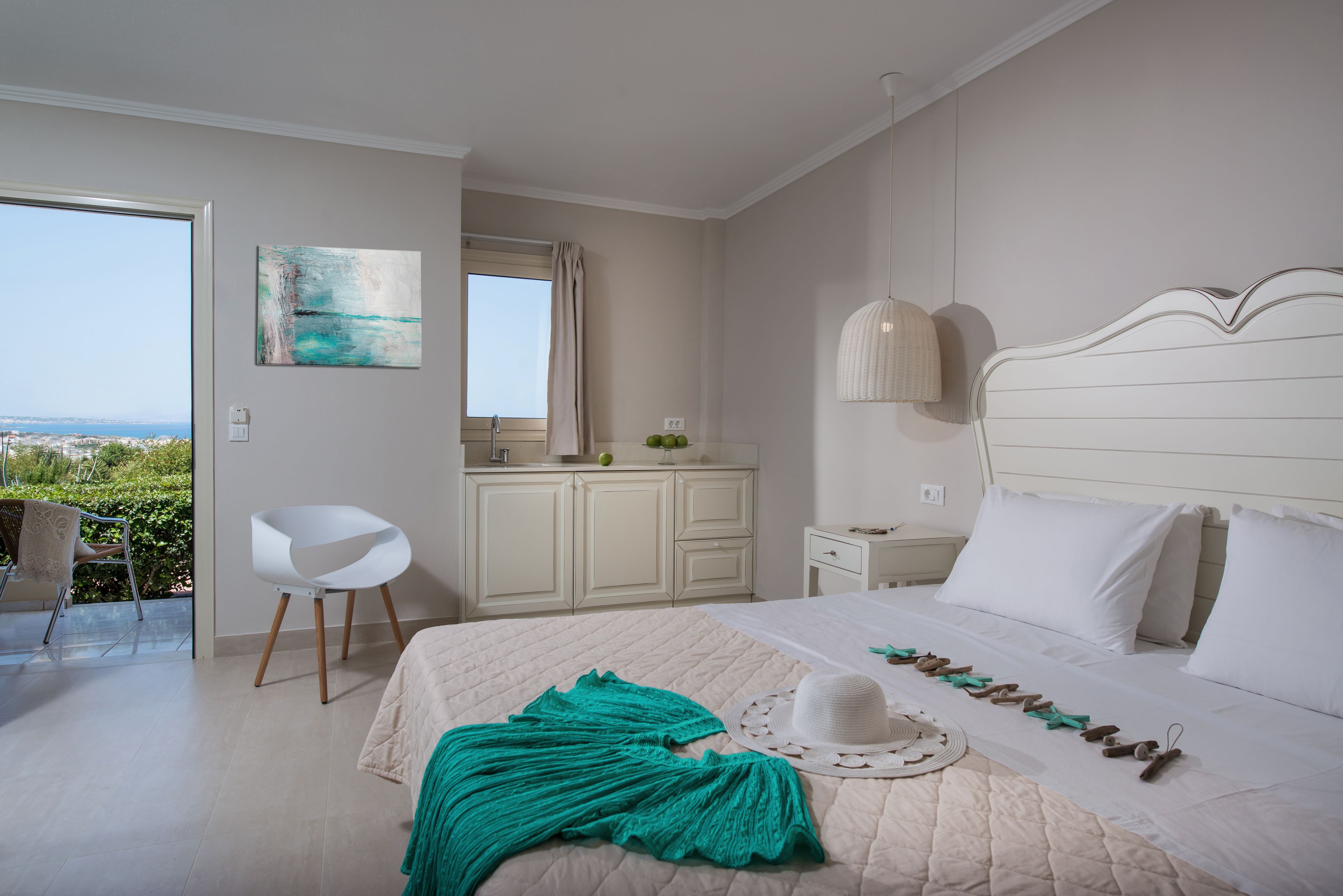 A bedroom with a bed, a chair, a desk, and a view of the outdoors.