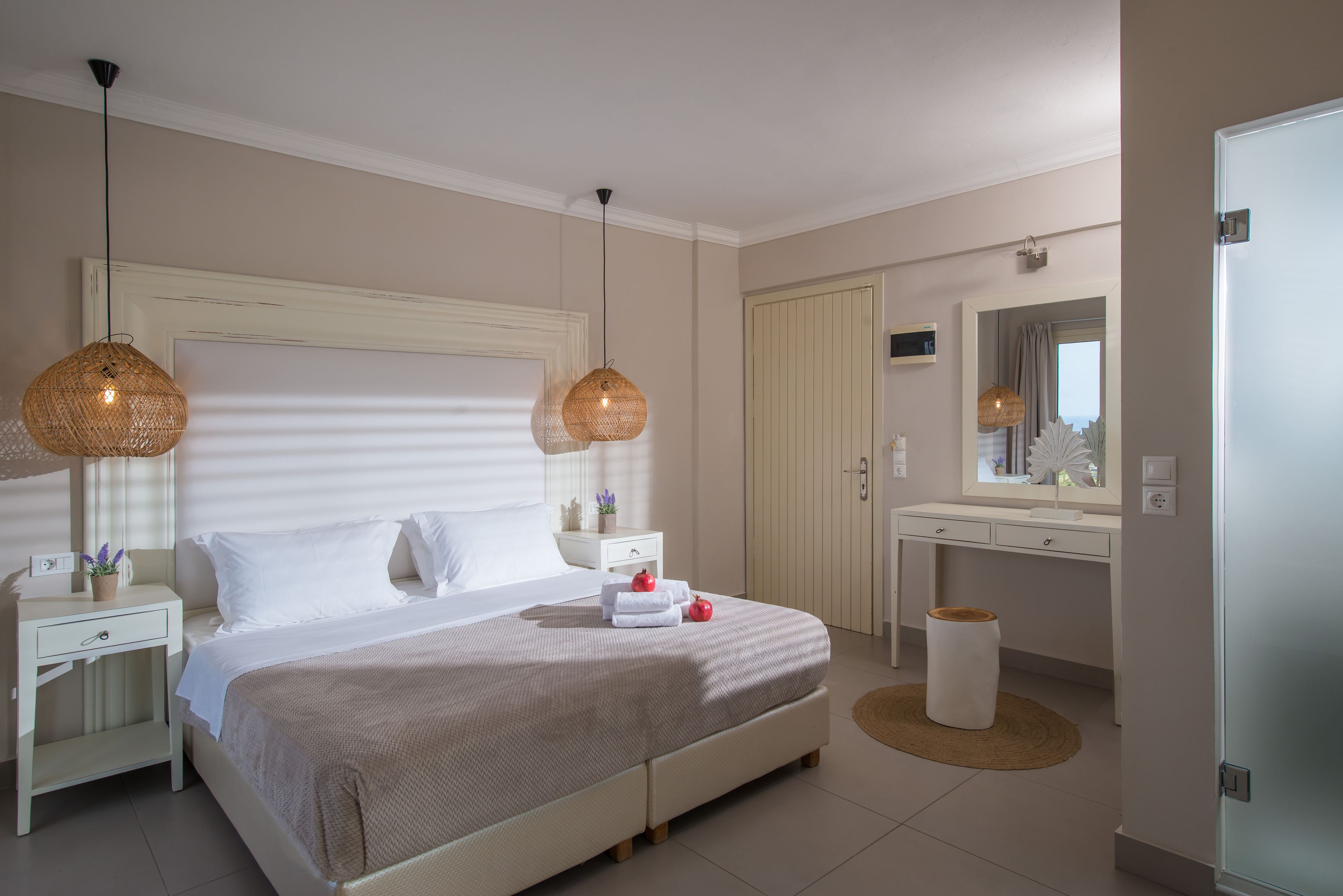 A bedroom with a bed, bedside tables, a dresser, a mirror, and a potted plant.