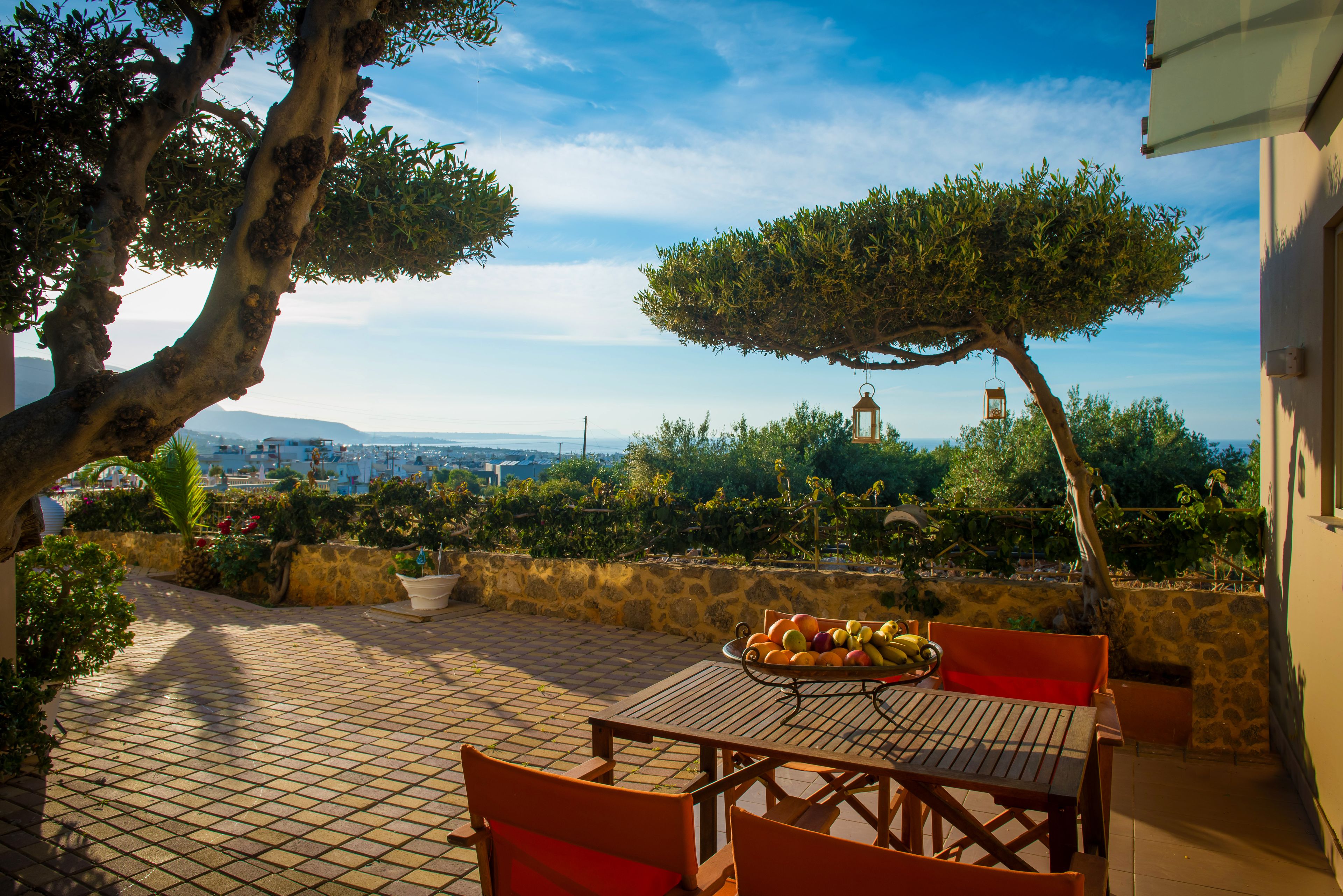 A patio with a table and chairs, a fruit bowl, and a view of the cityscape.