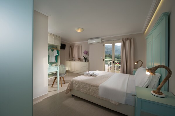 A bedroom with a bed, a desk, a chair, a wardrobe, and a balcony with a view. - Notos Heights Hotel & Suites (Malia)
