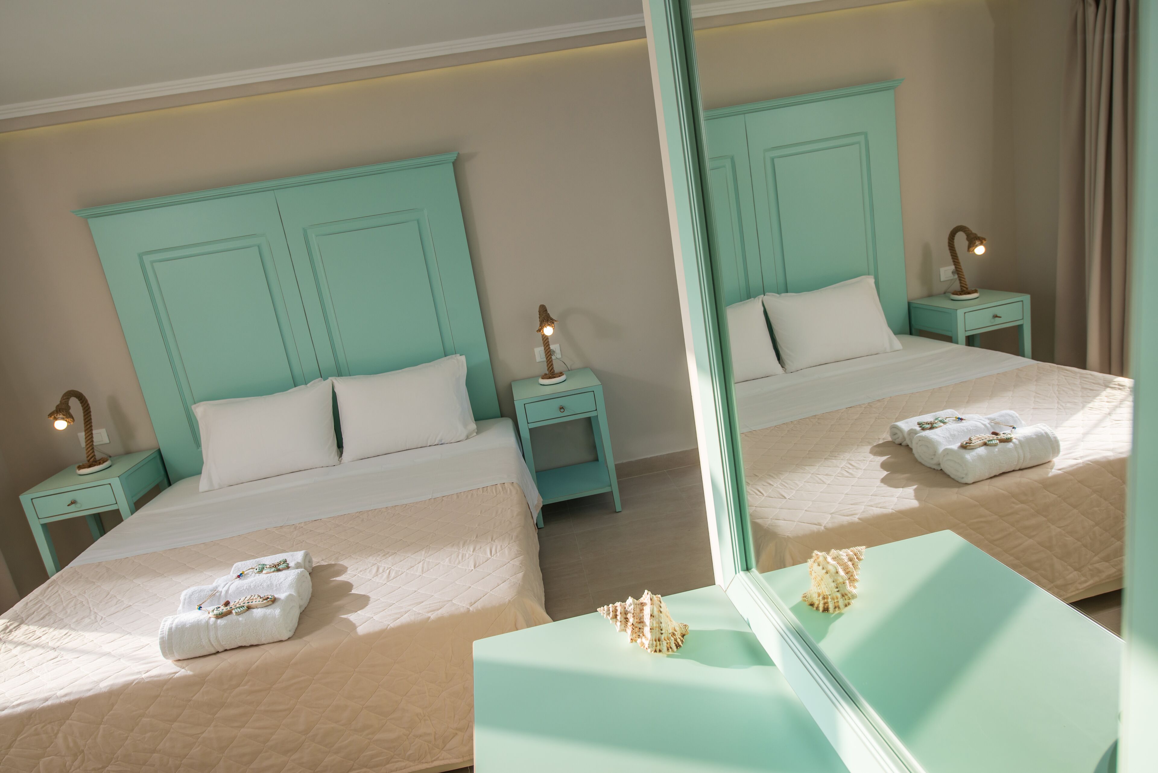 A mirrored room with two beds, each with a white headboard and matching nightstands.
