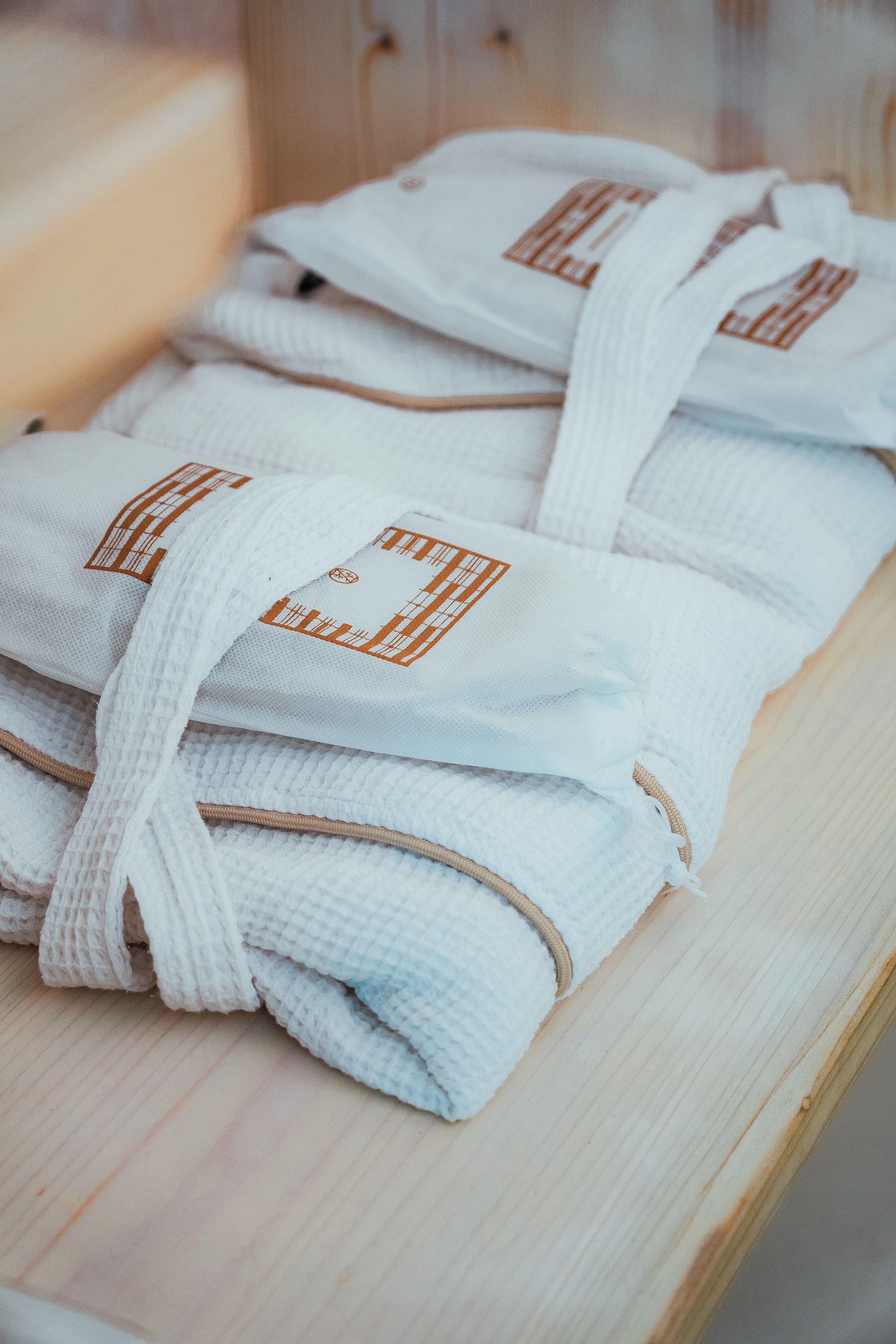 A stack of white towels with brown tags on a wooden surface.