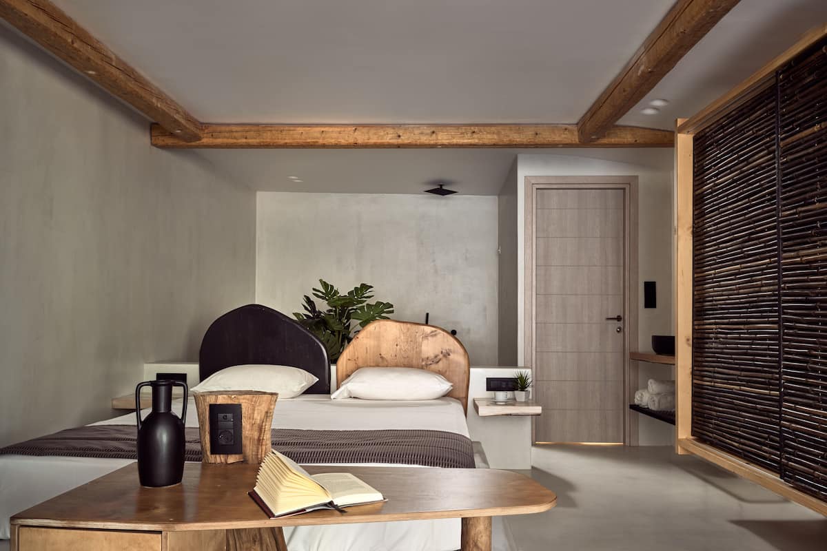 Ein modernes Schlafzimmer mit Bett, Nachttischen, einem Couchtisch und einem großen Fenster mit Jalousien.