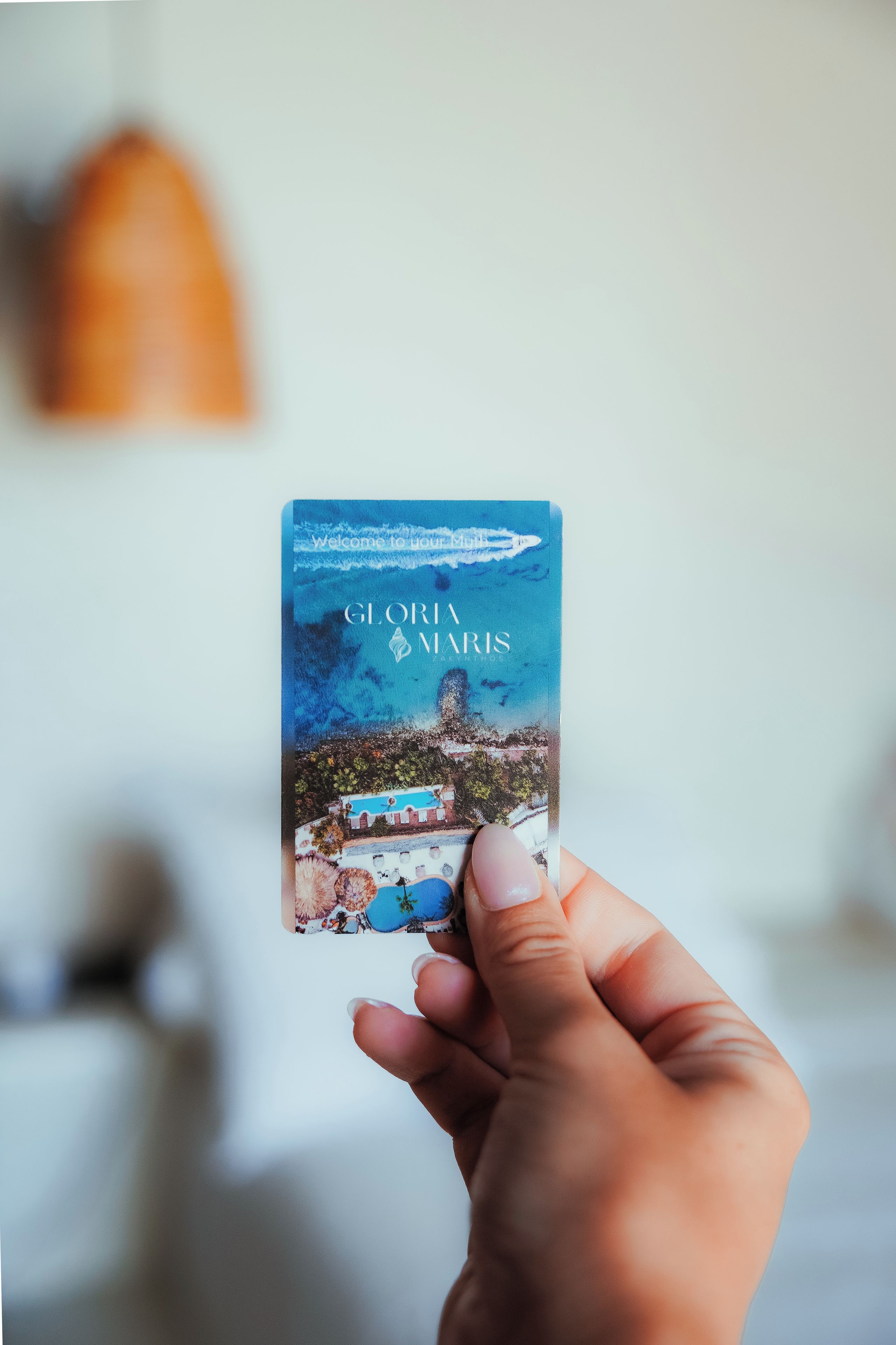 A hand holding a book titled 'GLORIA MARIS' with a coastal scene on the cover.