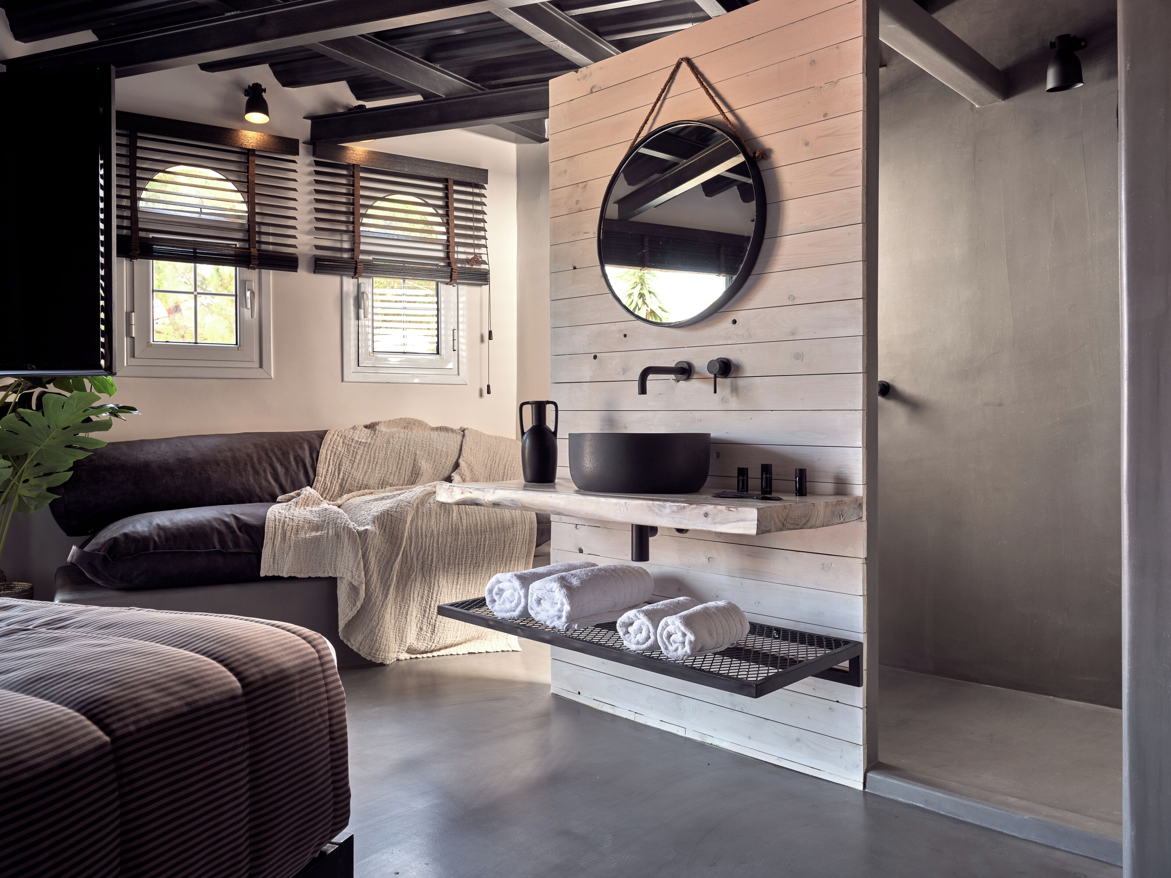A modern bathroom with a wooden vanity, a round mirror, and a black sink.