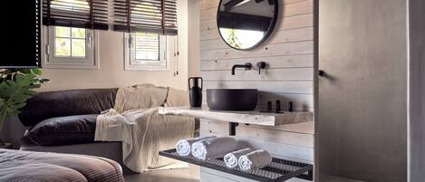 Un baño moderno con tocador de madera, un espejo redondo y un lavabo negro.