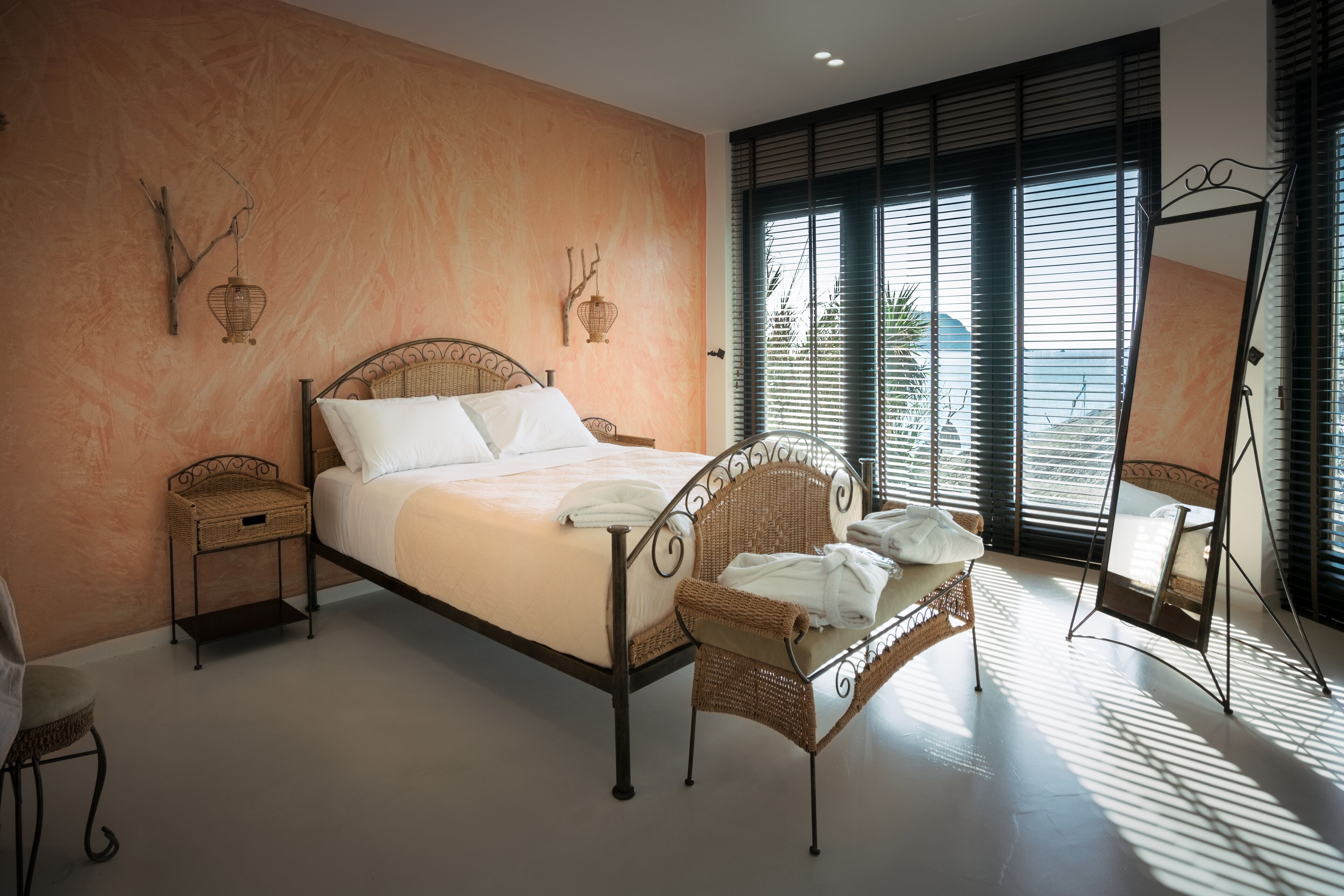 Un dormitorio con cama, muebles de mimbre, una mesita y un espejo.