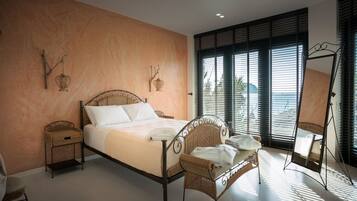 Un dormitorio con cama, muebles de mimbre, una mesita y un espejo.