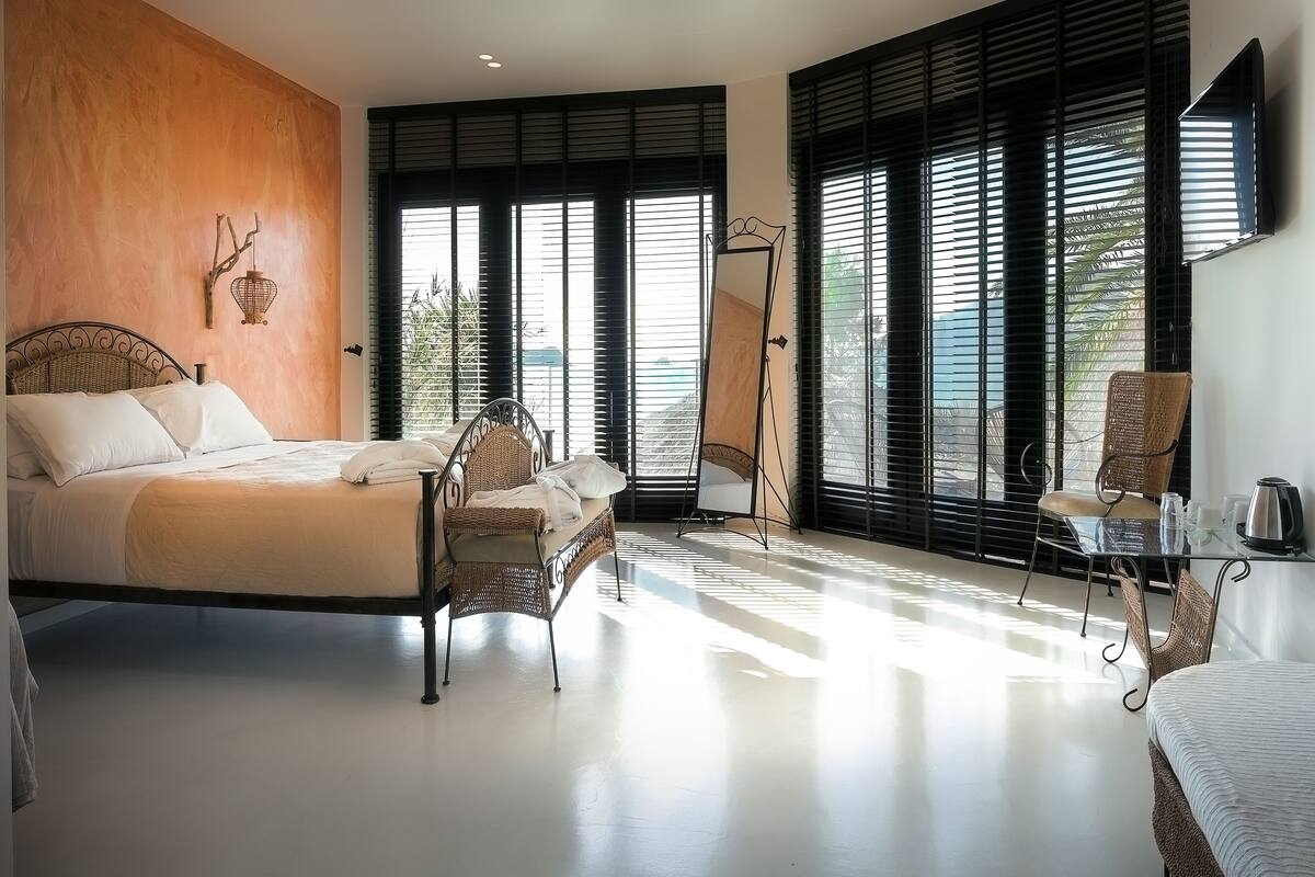 Ein Schlafzimmer mit Bett, Sessel, Tisch und Spiegel.