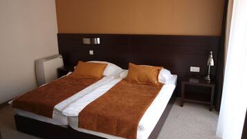 A double bed with a brown headboard, white bedding, and a bedside table with a lamp.