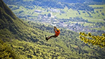 Iemand bungelt aan een bungeejumpingtouw, met een bergachtig landschap op de achtergrond.