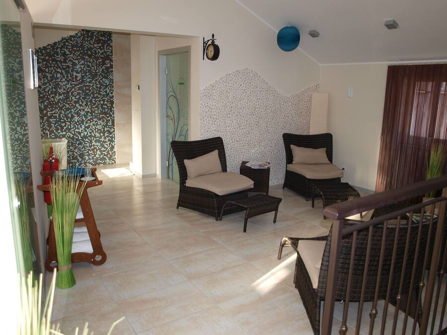 A spacious living area with two wicker chairs, a small side table, and a glass coffee table. A staircase is visible in the foreground.