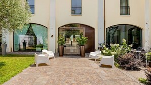 L’entrée d’un hôtel avec un patio abrité, des sièges en plein air et un jardin bien entretenu.