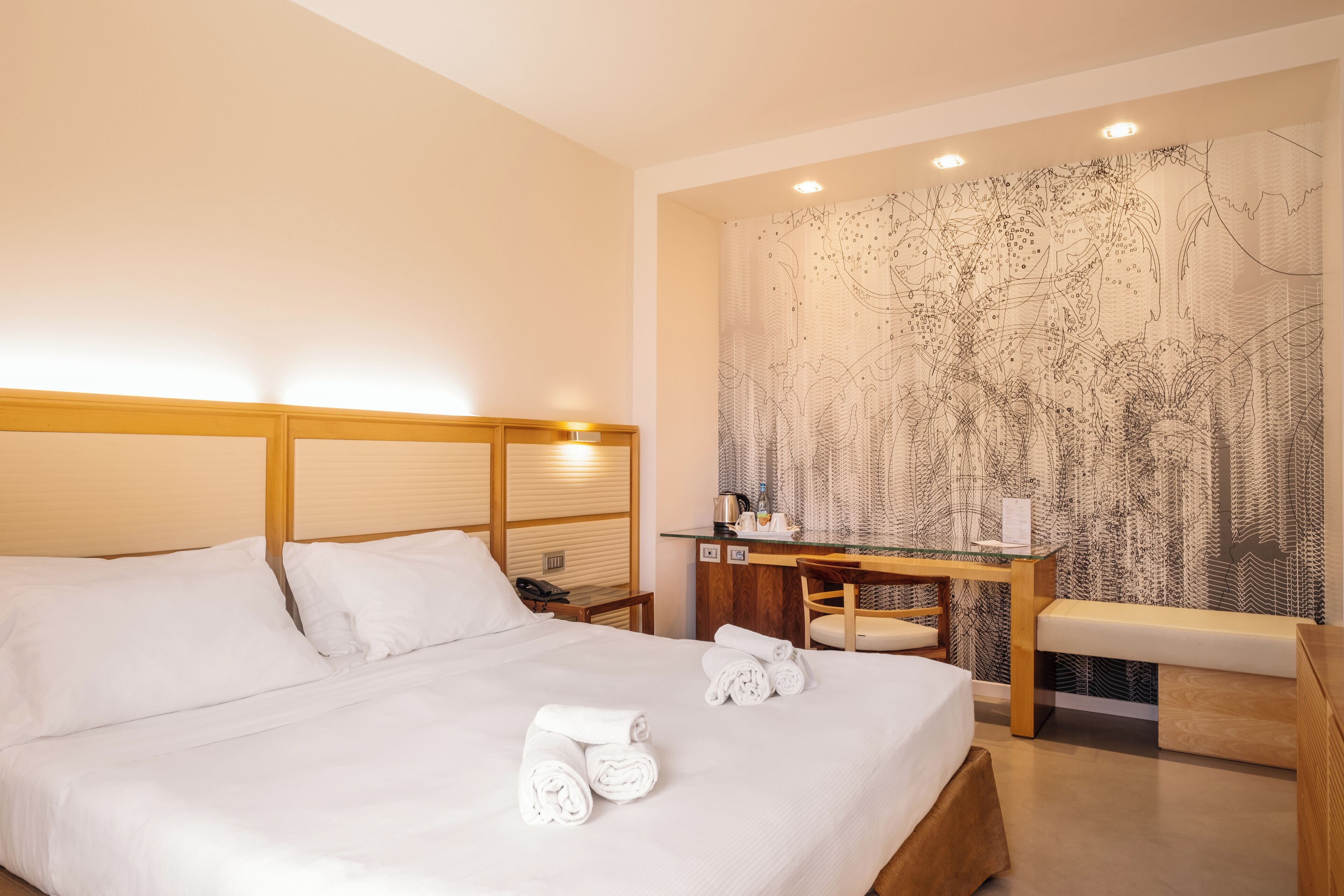 Ett hotellrum med en stor säng, ett skrivbord och en bänk.