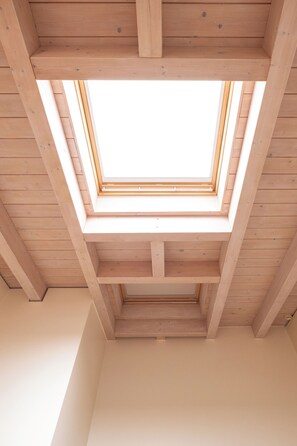 Une lucarne dans une pièce en bois dont le plafond est en pente.