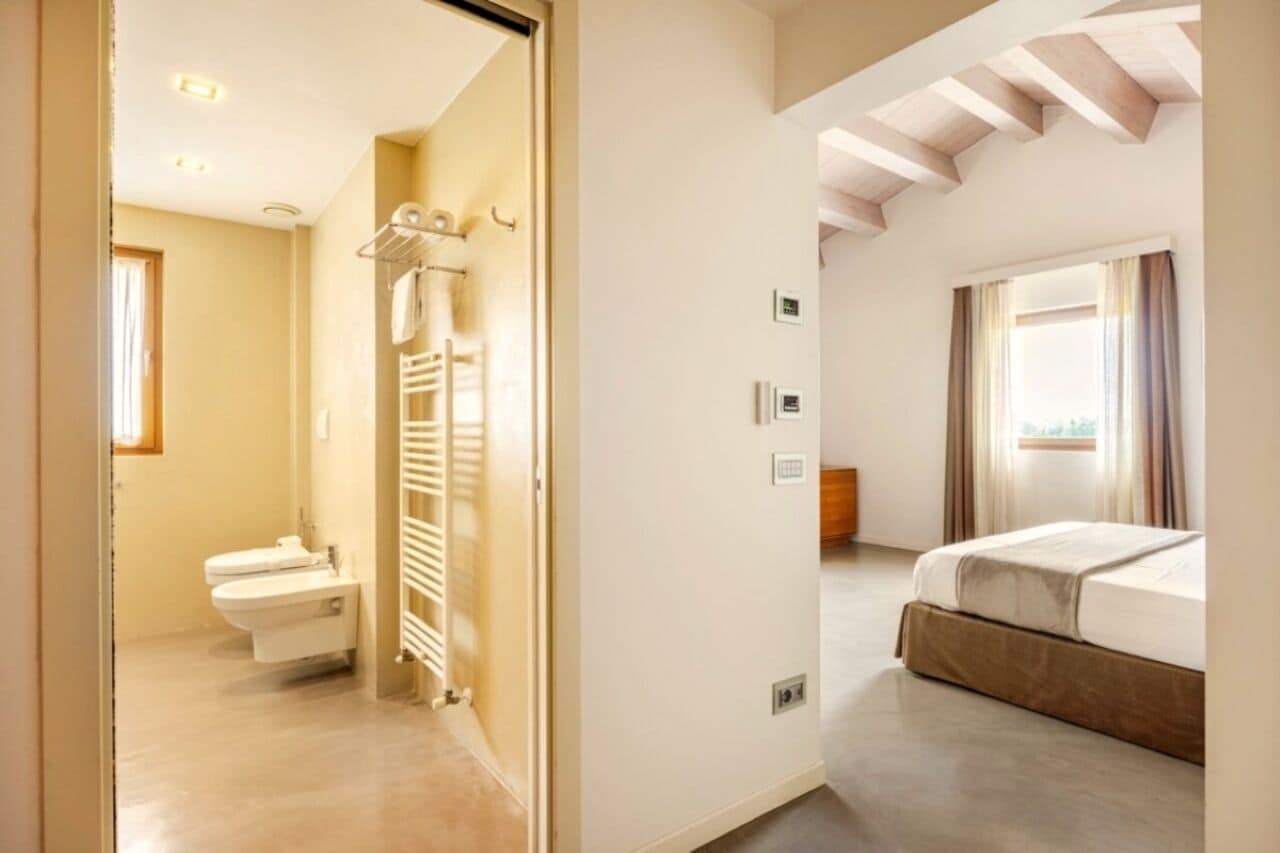 Ein Hotelzimmer mit Bad, einem Bett und einem Fenster mit Vorhängen.