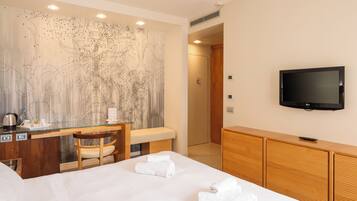 Una habitación de hotel con una cama, un escritorio con una silla, un televisor y una gran obra de arte abstracta en la pared.