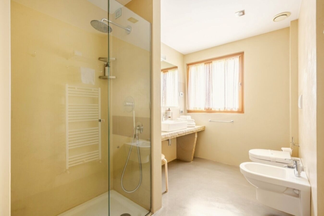A bathroom with a glass-enclosed shower, a sink, and a toilet.