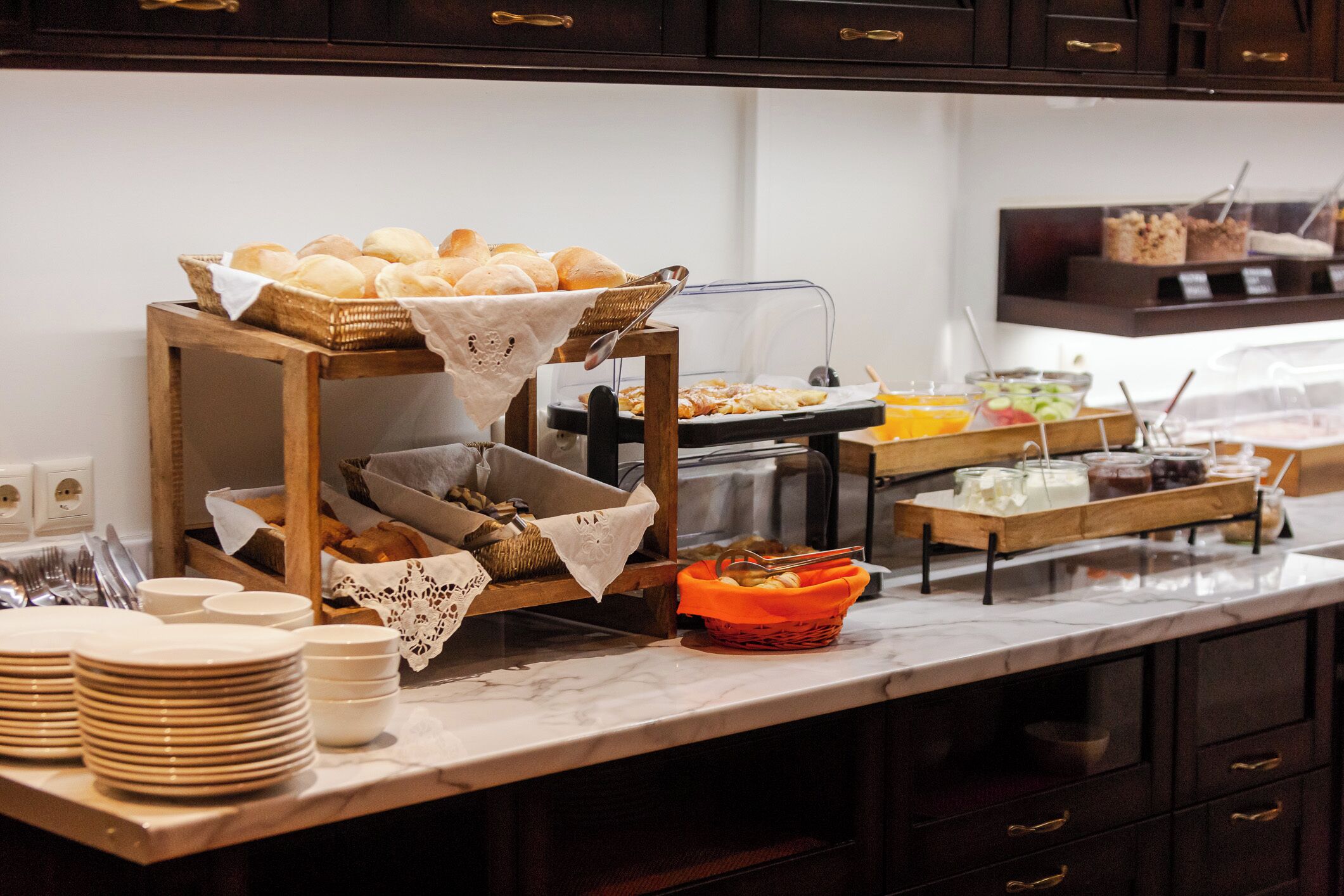A buffet setup with bread, fruits, and beverages.