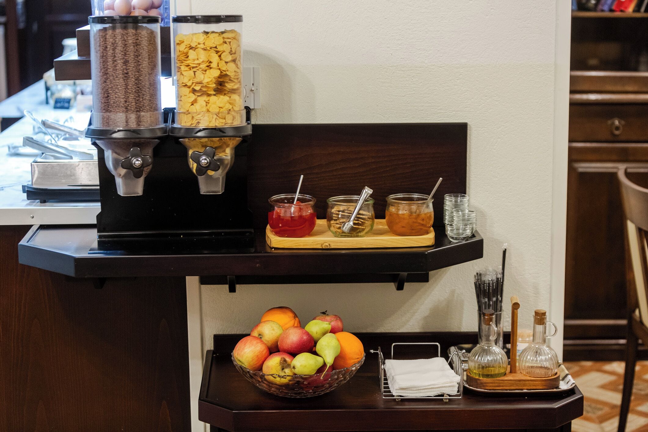 A breakfast bar with a coffee machine, a bowl of fruit, and condiments.