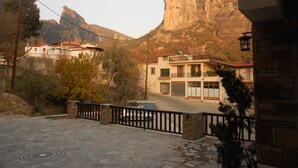 Zona residencial con calles adoquinadas de piedra, casas con balcones y un paisaje montañoso al fondo.