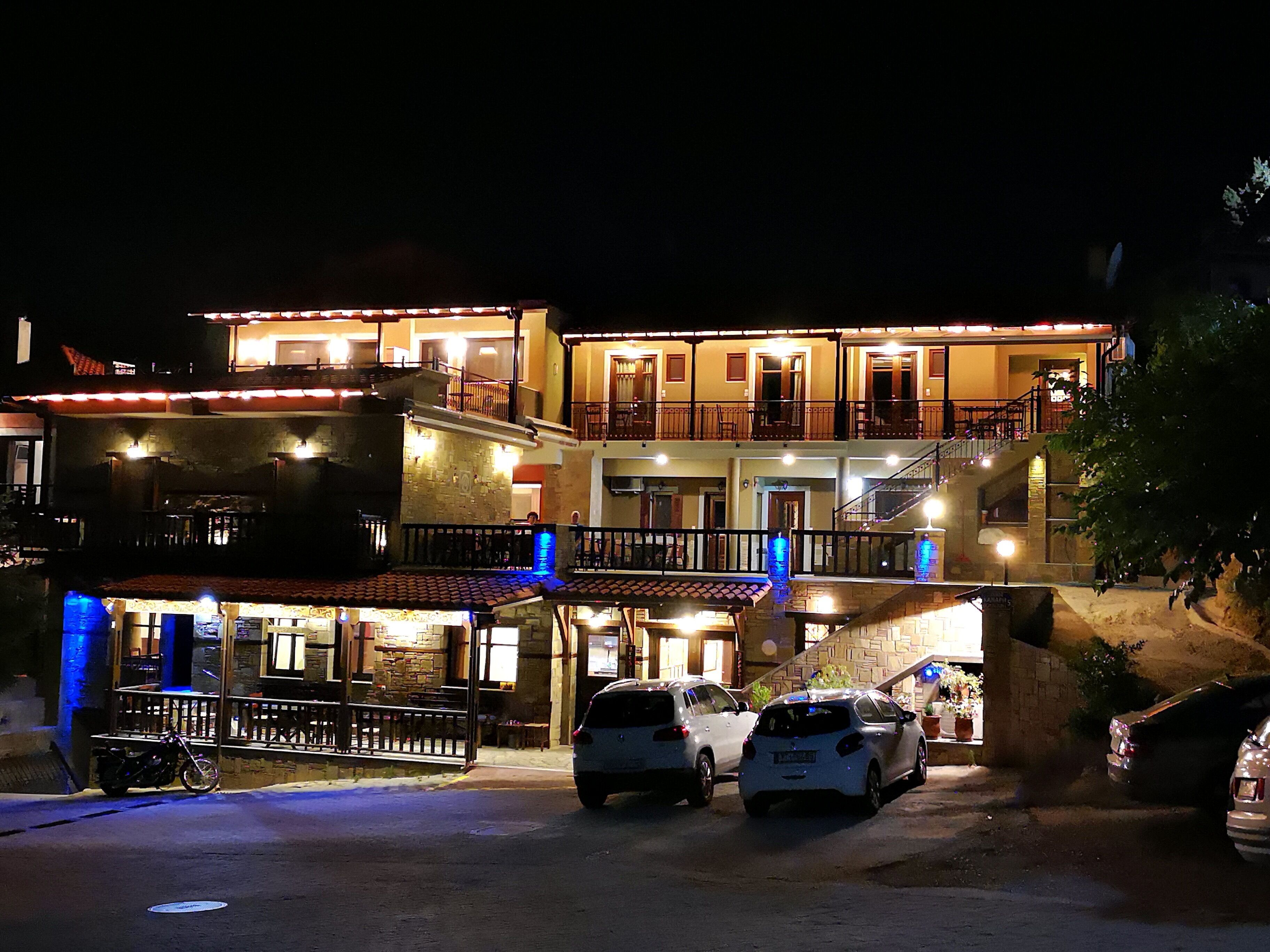 A multi-story hotel with balconies, a ground-level restaurant, and a parking area.