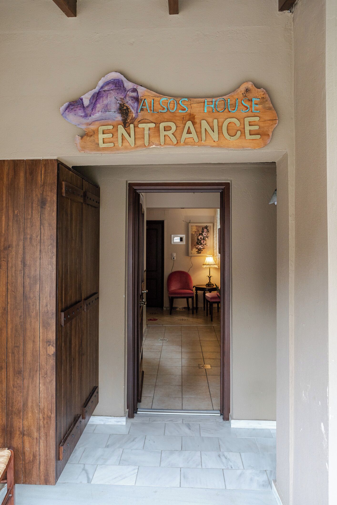 A wooden door with a sign above it reading 'ALSOS HOUSE ENTRANCE.'