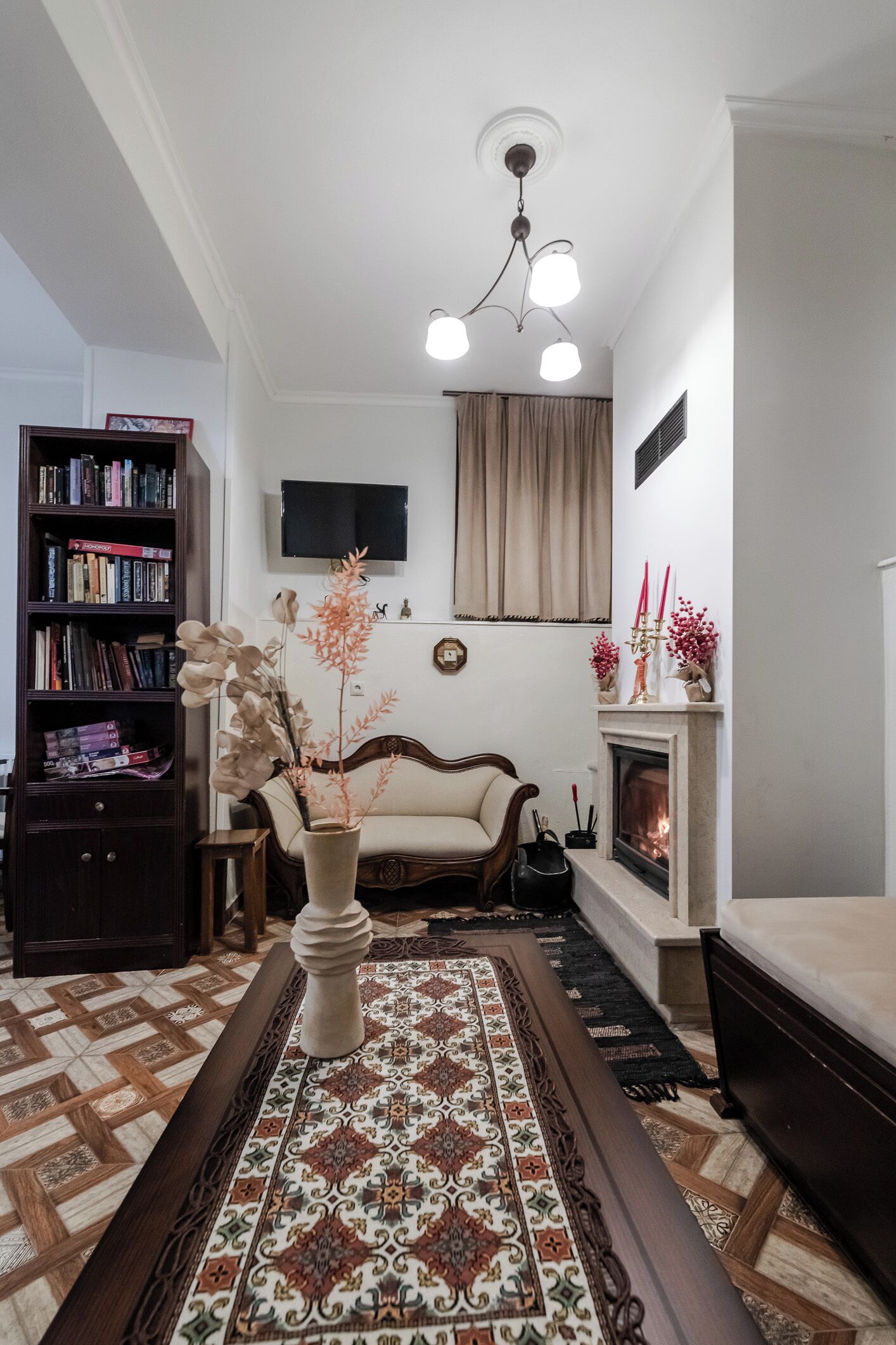 Una sala de estar con chimenea, un sofá, una estantería y un jarrón decorativo.