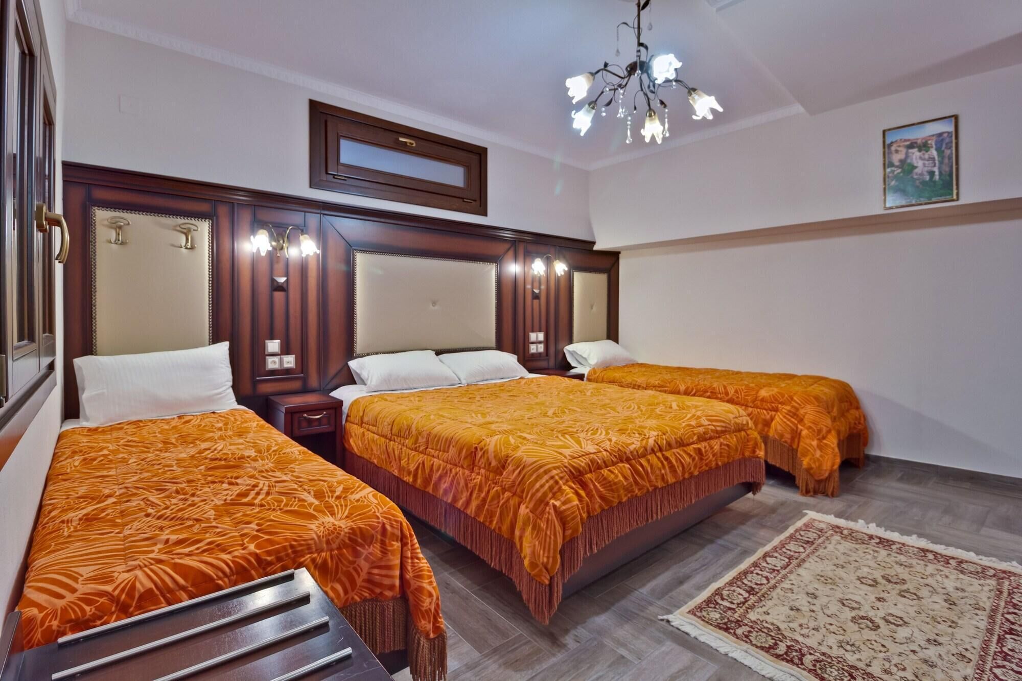 A hotel room with two beds, a wooden headboard, a chandelier, and a patterned rug.