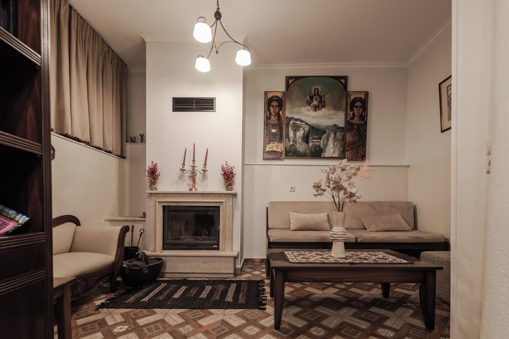 A living room with a fireplace, sofa, coffee table, and a painting on the wall.