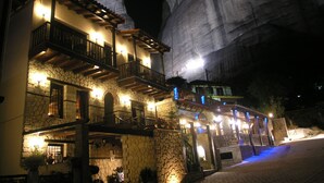 Un edificio de piedra con varios balcones y una gran formación rocosa al fondo.