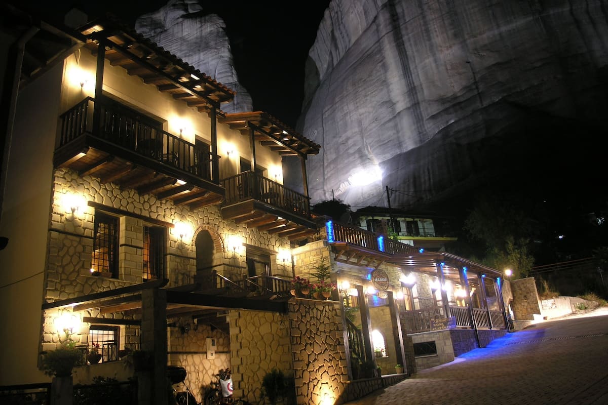 A stone building with multiple balconies and a large rock formation in the background.