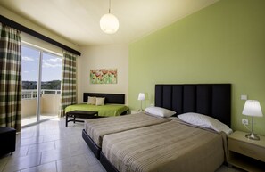 Ein Hotelzimmer mit zwei Betten, einem Balkon, einem Gemälde und Blick auf die Stadt.
