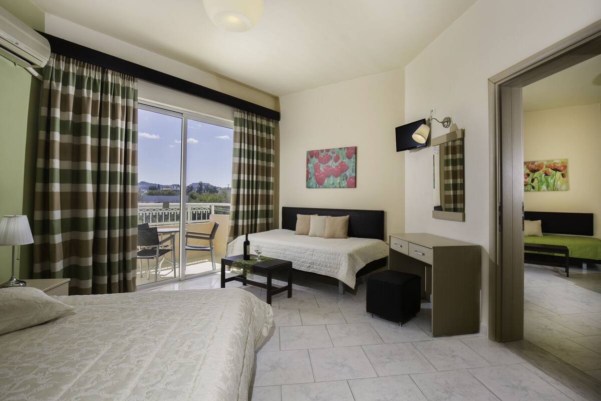 Une chambre d’hôtel comprenant un lit, un bureau, une chaise et un balcon avec vue sur le paysage.