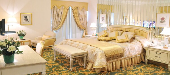 A luxurious bedroom with a large bed, a bedside table, a chair, and a bench.
