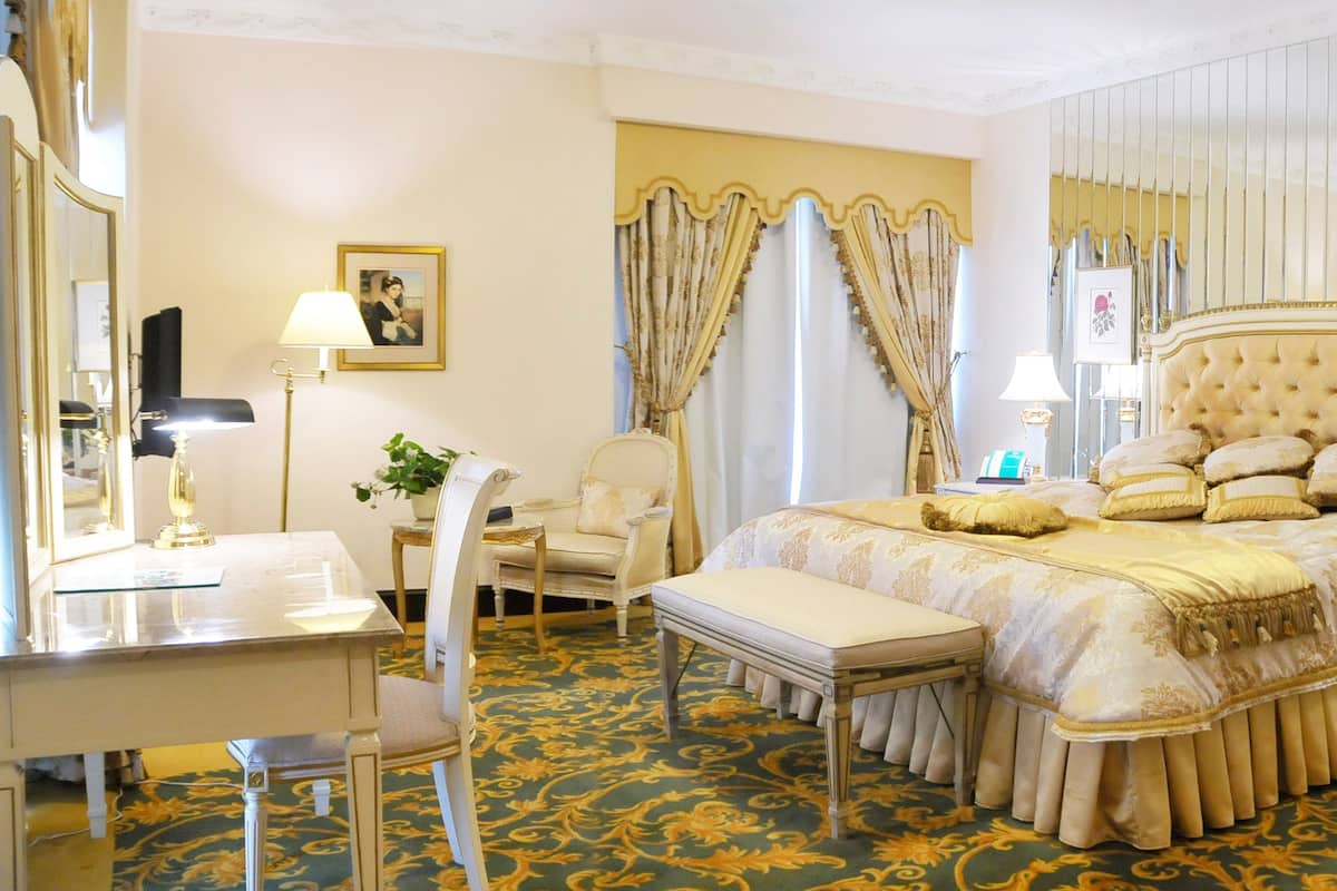 Een luxueuze slaapkamer met een groot bed, een nachtkastje, een stoel, een bureau en een spiegel.