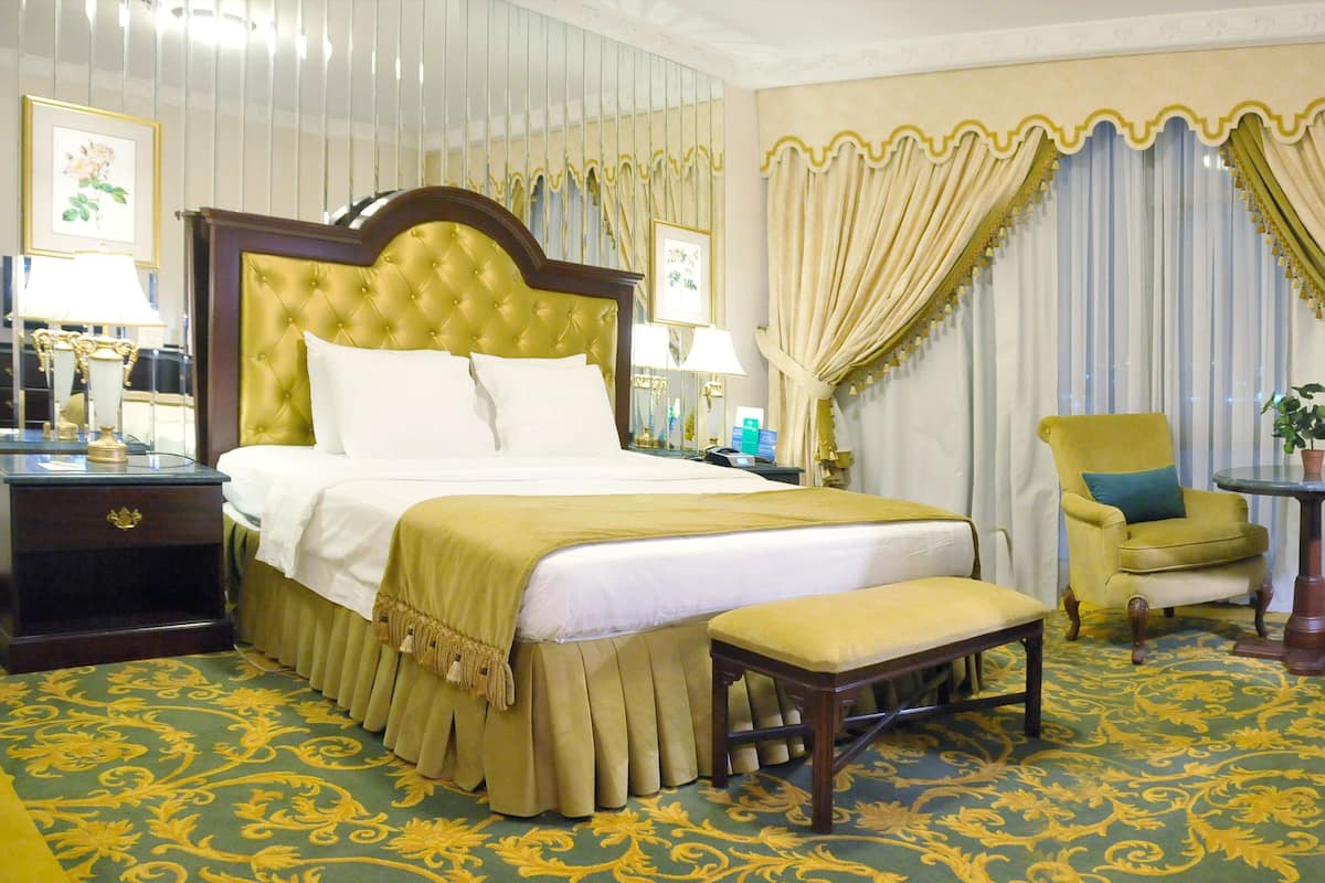 Een hotelkamer met een groot bed, nachtkastje, stoel, bureau en televisie.