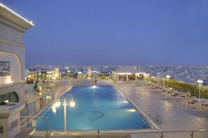 A rooftop pool with a city view, outdoor seating, and a lifebuoy.
